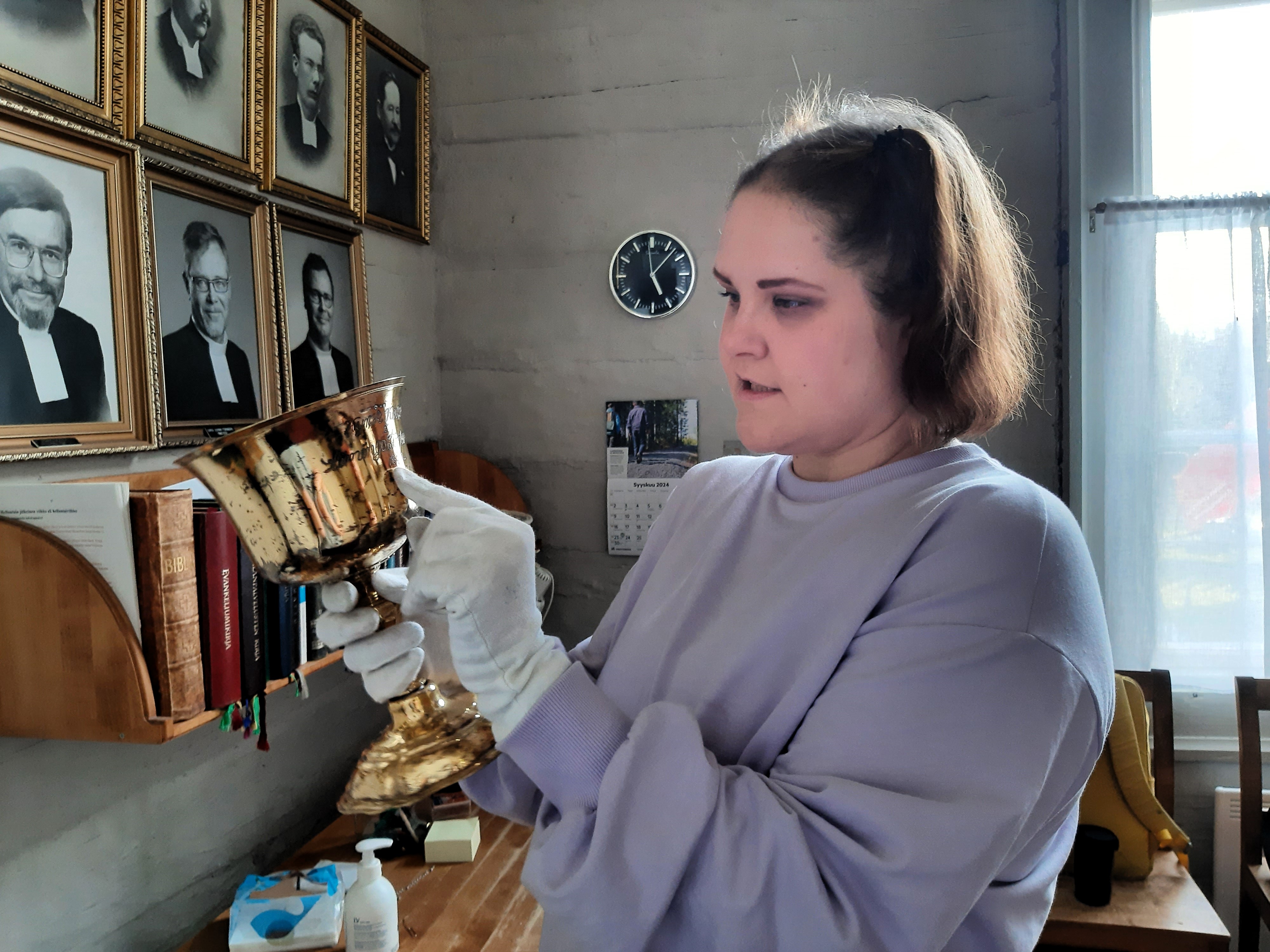 Hilla Nättilä tutkii vanhaa ehtoollismaljaa.